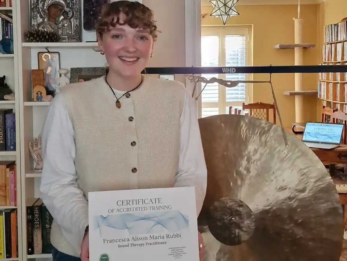 Person holding certificate beside a large gong.