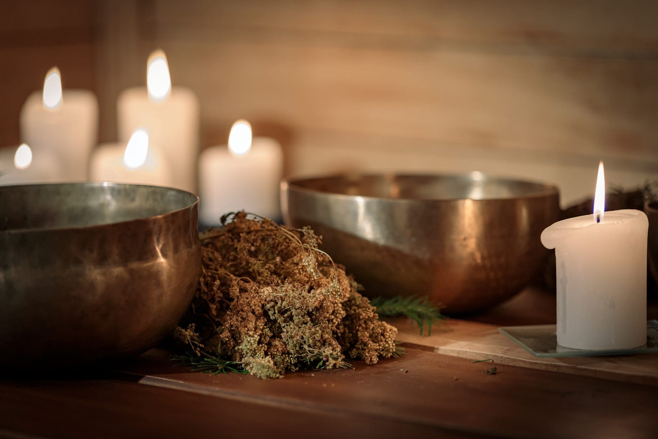 Lit candles and bowls on wooden surface.