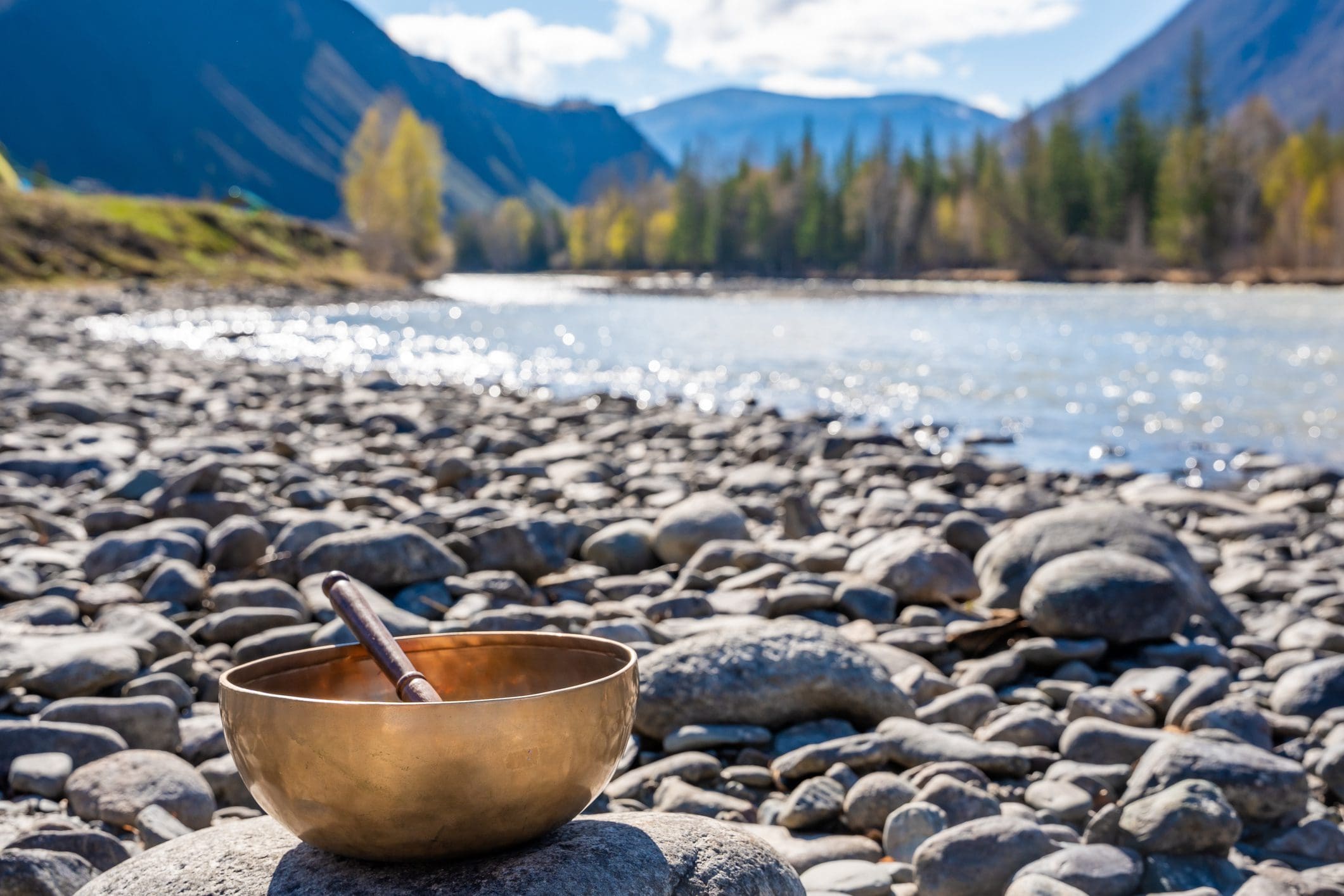Tibetan bowl on rocky riverbank, scenic background.